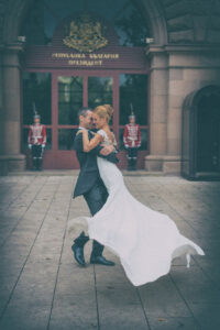 Младоженци танцуват пред официалния вход на Президентството в София, пазен от гвардейци. Иконична сватбена фотография от Симеон Сълов.