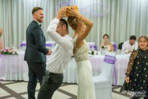 Булка и младоженец чупят традиционна сватбена питка над главите си, изпълнявайки ритуал кой ще командва вкъщи, в Ресторант "ЛАУРА". Снимка от сватбен фотограф Симеон Сълов.