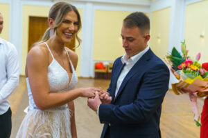 Щастлива булка се смее, докато младоженецът поставя сватбения й пръстен в зала "Хиподрума". Кадър от сватбен фотограф Симеон Сълов.