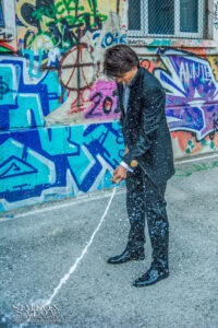 Абитуриент от Френската гимназия в София пръска шампанско пред стена с графити по време на своето изпращане.