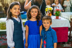 Портрет на три усмихнати деца-гости на свето кръщение, позиращи в храма – кадър от фотограф за кръщене.