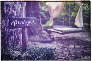 Декоративна дървена табела с надпис "Ритуал", указваща мястото за изнесен сватбен ритуал в "Приказната Градина", детайл от сватбата, заснет от сватбен фотограф Симеон Сълов.