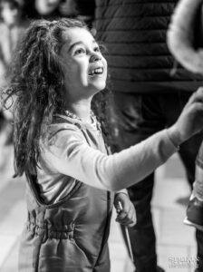 Черно-бял портрет на малко момиченце, което гледа с възхищение и радост по време на кръщенето на Борис. Кадър от професионален фотограф за кръщене Симеон Сълов.