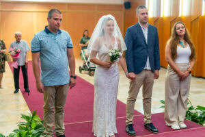Младоженците Мирела и Марио, заедно със своите кумове, стоят пред длъжностното лице по време на гражданския брак в зала Триадица. Кадър от професионален сватбен фотограф Симеон Сълов.
