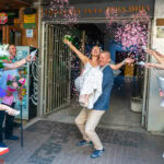 Младоженецът Марио носи на ръце булката Мирела при излизането им от ритуална зала Триадица, докато гостите ги обсипват с конфети. Кадър от професионален сватбен фотограф Симеон Сълов.