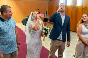 Младоженците Мирела и Марио пият шампанско "на екс" в ритуална зала Триадица, заобиколени от усмихнатите си кумове. Кадър от професионален сватбен фотограф Симеон Сълов.