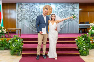 Новото семейство Мирела и Марио позират за официална снимка със своето брачно свидетелство в ритуална зала Триадица. Кадър от професионален сватбен фотограф Симеон Сълов.