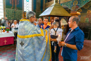 Свещеник извършва миропомазване, помазвайки челото на Борис със свето миро – ритуал, заснет от фотограф за кръщене.