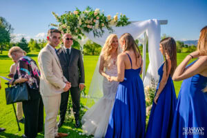 Булката приема щастливи поздрави и прегръдки от своите шаферки, облечени в сини рокли, след края на сватбената си церемония. Кадър от сватбен фотограф Симеон Сълов.