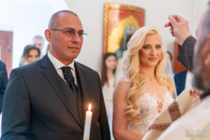 Свещеникът дава своята благословия на младоженците Бояна и Вальо по време на ритуала по венчавка. Кадър от сватбен фотограф Симеон Сълов.