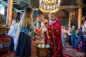Свещеник извършва Светото тайнство Кръщение, като потапя малкия Светозар в купела със светена вода.