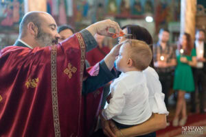 Свещеник извършва ритуала по постригване на косата на малкия Светозар, държан от кръстницата си по време на Свето Кръщение.