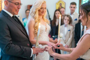 Кумата извършва ритуала по размяна на венчалните халки на ръцете на младоженците Бояна и Вальо. Кадър от сватбен фотограф Симеон Сълов.