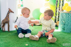 Малкият рожденик Светозар си играе със свое приятелче на пода пред украсата – кадър от фотограф за детски рожден ден.