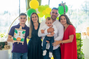 Семейството на Светозар позира за снимка на първия му рожден ден, а по-големият му брат държи табелка с цифрата 1 – кадър от фотограф за детски рожден ден.