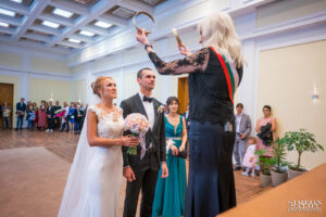 Длъжностното лице държи ритуална корона над главите на булката и младоженеца по време на гражданския брак. Кадър от сватбен фотограф.