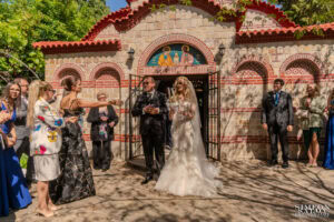 Гостите поздравяват щастливите младоженци Бояна и Вальо пред църквата след края на венчавката им. Кадър от сватбен фотограф Симеон Сълов.