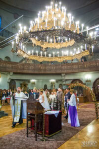 Свещеник води младоженците и кумата в ритуалното шествие „Танцът на Исая“ по време на венчавка в храм „Света Параскева“.