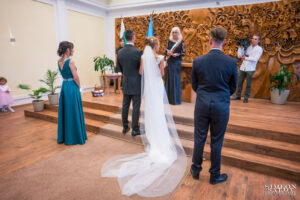 Младоженци и кумове в гръб пред длъжностното лице по време на официалната церемония в Обредна зала "Хиподрума". Кадър от сватбен фотограф София.