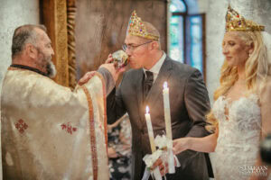 Младоженецът Вальо отпива от общата чаша с вино, подадена му от свещеника, по време на църковния брак. Кадър от сватбен фотограф София Симеон Сълов.