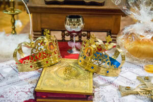 Сватбени корони (венчала), евангелие и чаша с вино, подготвени върху олтара за ритуала по църковен брак в храм „Света Параскева“.