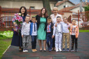 Детски фотограф за дипломиране: Група момчета позират щастливо със своите усмихнати учителки, които държат букети. Кадър от фотограф Симеон Сълов.