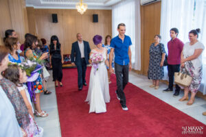 Младоженците влизат в Обредна зала „Сердика“, посрещнати от гостите преди началото на гражданската церемония.