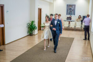 Сватбен фотограф Обредна зала "Средец": Младоженците влизат по коридора на залата, водени от длъжностно лице, под аплодисментите на кумовете. Кадър от Симеон Сълов.