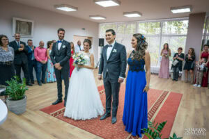 Сватбен фотограф в зала "Оборище": Щастливи младоженци и кумове се усмихват, докато слушат речта на длъжностното лице по време на гражданския брак. Кадър от Симеон Сълов.