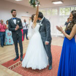 Сватбен фотограф в зала "Оборище": Младоженците се целуват за първи път като семейство, а булката вдига букета си под аплодисментите на кумовете. Кадър от Симеон Сълов.